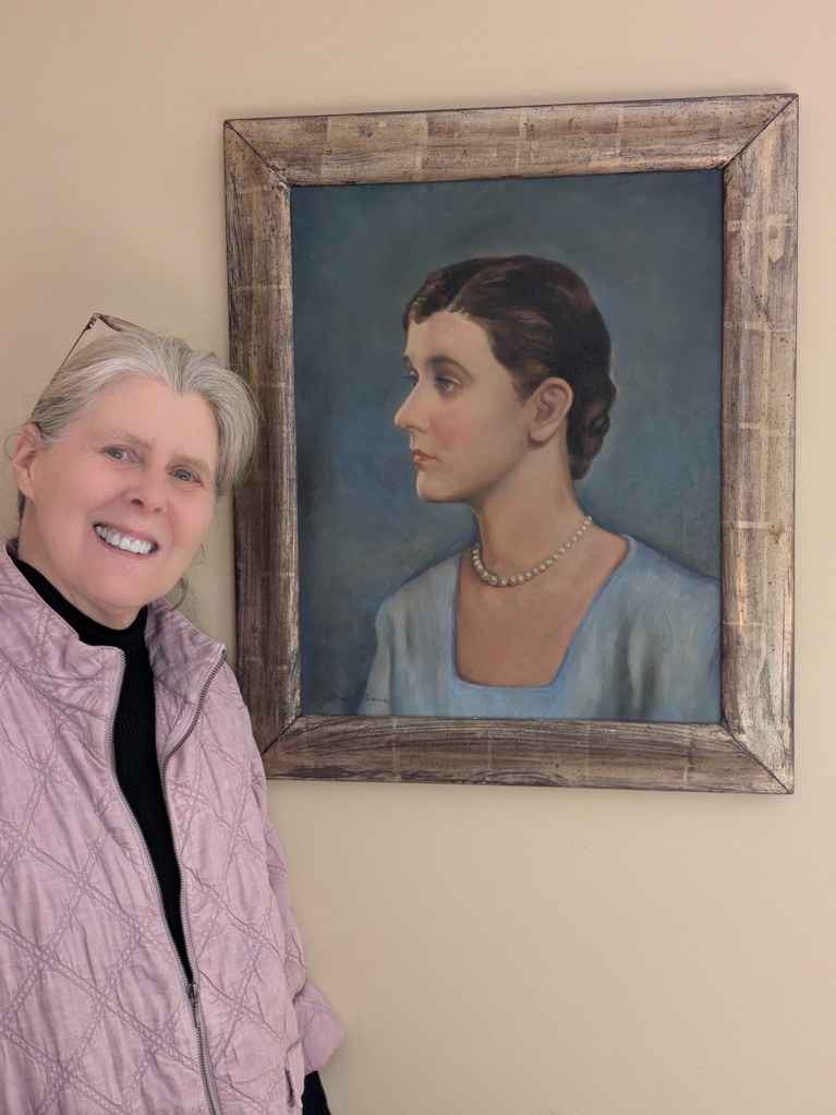 Marla Miller beside a painted portrait of an early twentieth-century woman